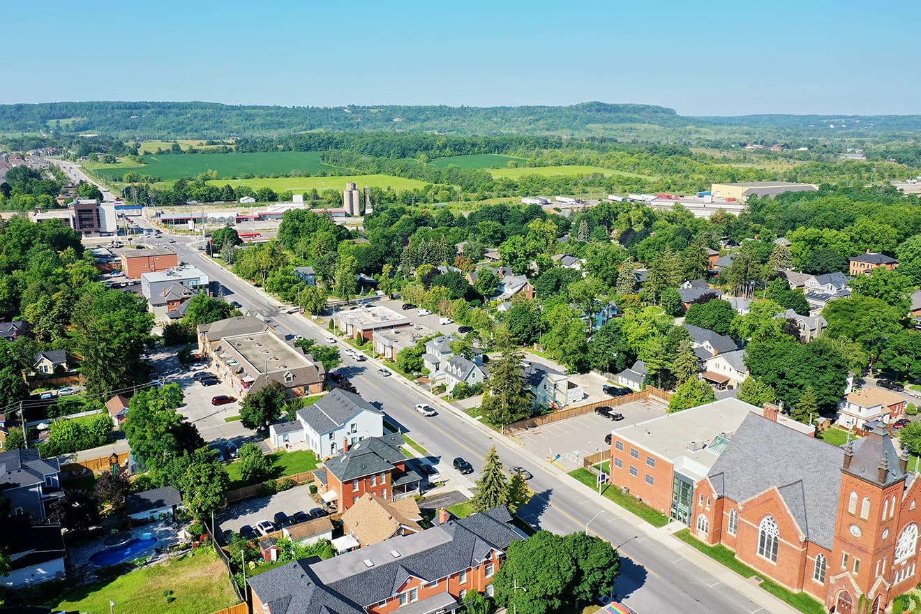 Aerial view of a small town with tree-lined streets, homes, businesses, and surrounding farmland.
