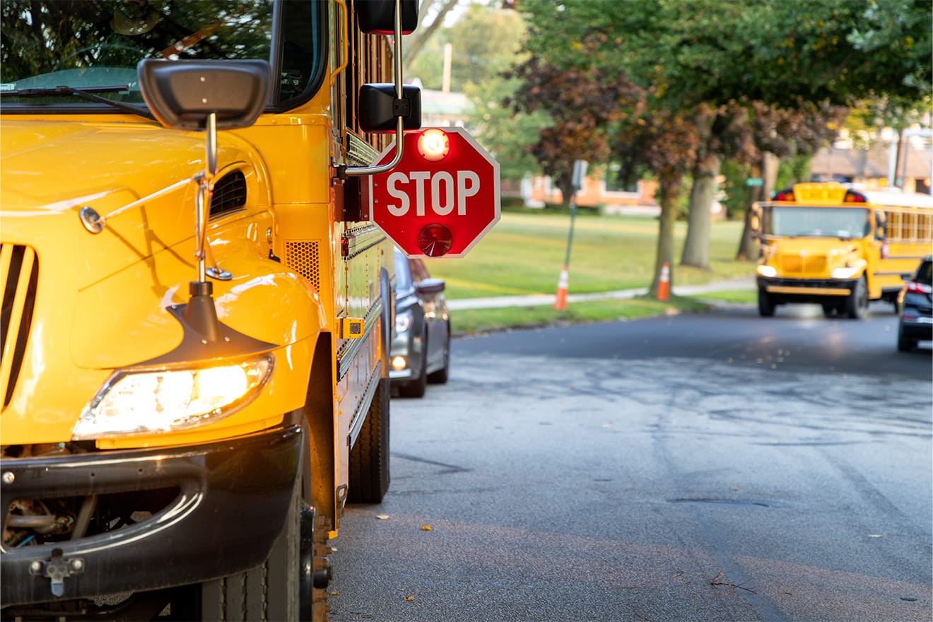 Yellow school bus with an extended red stop sign on a residential street.